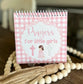Small spiral-bound book titled 'Prayers for little girls' with a pink checkered design on a wooden surface.
